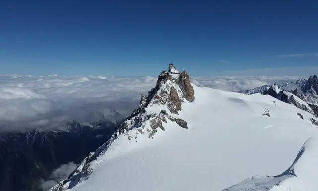 Szczyt Aiguille du Midi w Alpach Włoskich, z widokiem na morze chmur i ośnieżone góry.
