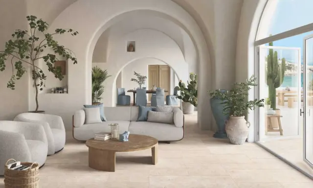 Un salon lumineux avec des arches, des plantes et un canapé confortable. Le sol en carrelage clair est idéal pour ce style méditerranéen. Quel revêtement de sol choisir ?