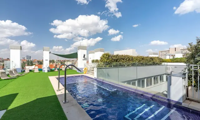 Resa Claudio Coello Madrid: piscina en azotea con césped artificial, tumbonas y vistas urbanas.