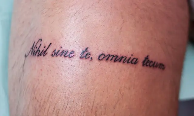 Tatuaż z łacińską sentencją "Nihil sine te, omnia tecum" na skórze.
