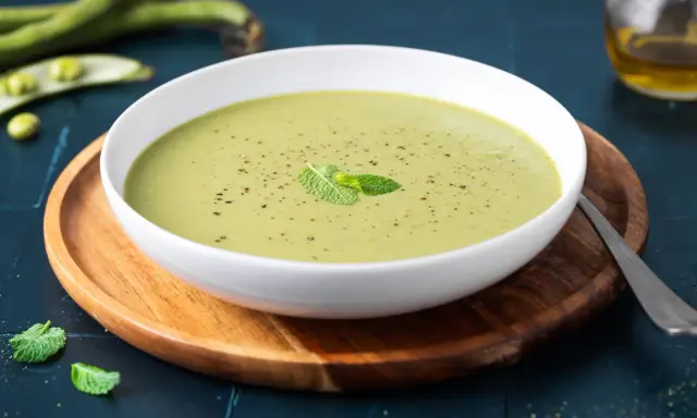 Una ciotola di cremoso purè di fave, guarnito con menta fresca e pepe nero, pronto per essere gustato.