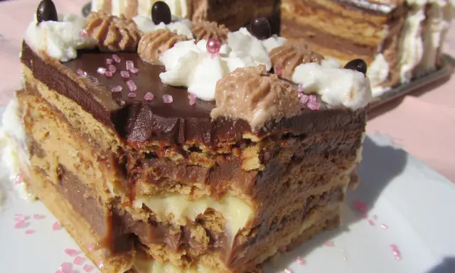 Un trozo de tarta de la abuela, con capas de galleta y crema de chocolate, decorada con nata y virutas rosas.