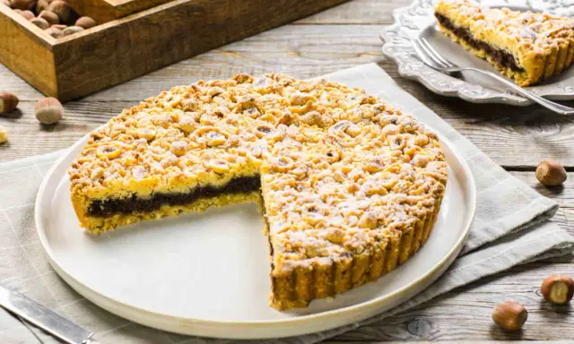 Sbriciolata alla Nutella con tante nocciole croccanti, un dolce invitante su un piatto bianco, pronto per essere gustato.