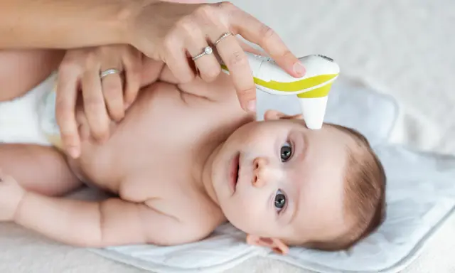 Mama mierzy temperaturę niemowlaka termometrem bezdotykowym.