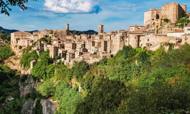 Un affascinante borgo toscano da visitare, arroccato su una rupe tufacea, con case in pietra e torri che si stagliano contro il cielo azzurro.