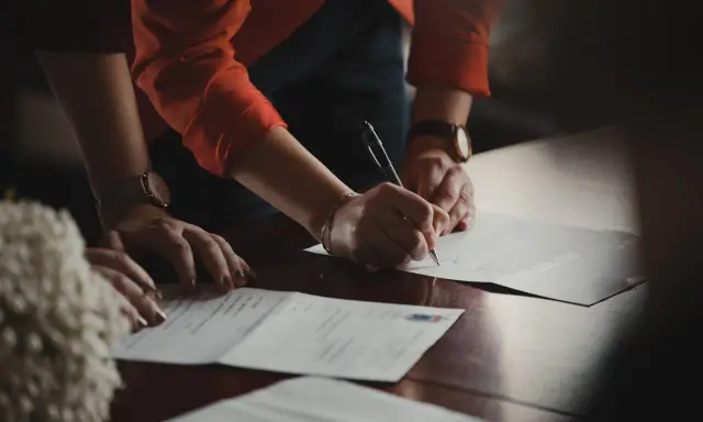 Manos de testigos boda civil firmando documentos importantes.