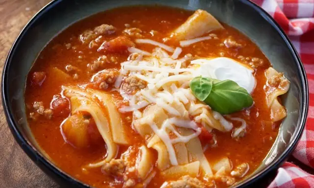 Herzhafte Lasagne Suppe mit Hackfleisch, Nudeln und Käse, garniert mit einem Klecks Sauerrahm und Basilikum.