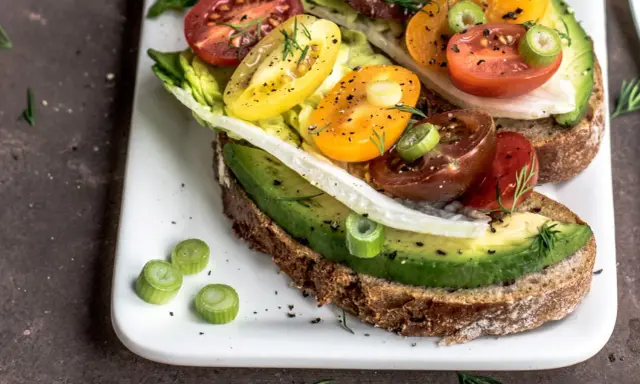 Herzhafte Avocado-Tomaten-Toasts auf Vollkornbrot, garniert mit Frühlingszwiebeln und Dill. Perfekt als kalorienarme Snacks für zwischendurch.