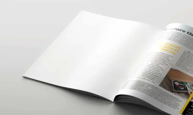 Pagina di rivista aperta, con testo "Essential vacation items" su carta satinata.