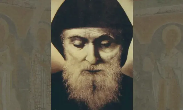 Portret brodatego mężczyzny w czapce, przypominającego świętego Szarbel, którego cuda są znane. W tle niewyraźne postacie.
