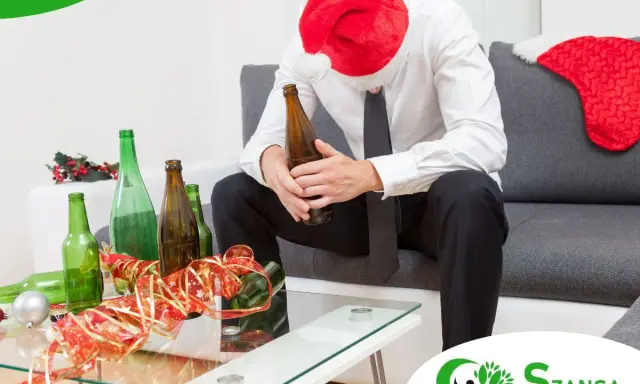 Smutny mężczyzna w czapce Mikołaja siedzi z butelką piwa, otoczony pustymi butelkami. Szukasz co zamiast alkoholu?