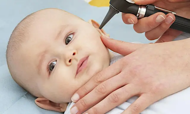Esame dell'orecchio di un neonato per diagnosticare un'otite.
