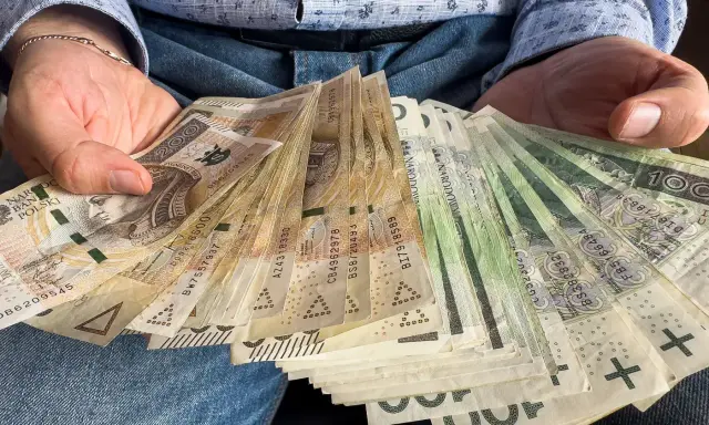 Ręce trzymające stos banknotów 100 zł i 200 zł. To darowizna od rodziców na nowy cel.