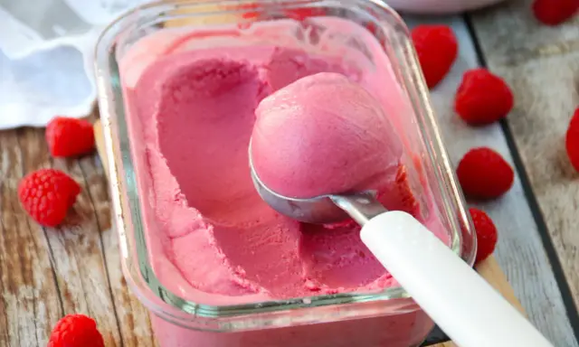 Glace framboise sans sorbetière, on dirait qu'elle est faite avec du lait concentré. Une boule est prélevée avec une cuillère.