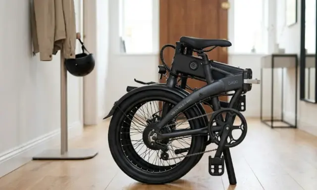 Składany rower elektryczny, idealny do miejskich podróży, wygląda jak nowoczesny rower amerykański. Obok wisi kask.