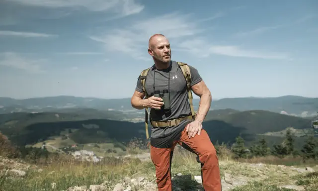 Mężczyzna w letnim stroju górskim: koszulka, spodnie trekkingowe i plecak. Idealny przykład, jak się ubrać w góry latem.