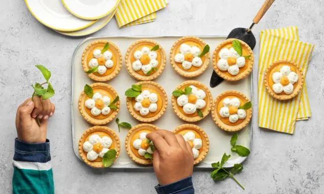 Douces tartelettes à l'abricot, décorées de crème fouettée et de menthe, prêtes à être dégustées.