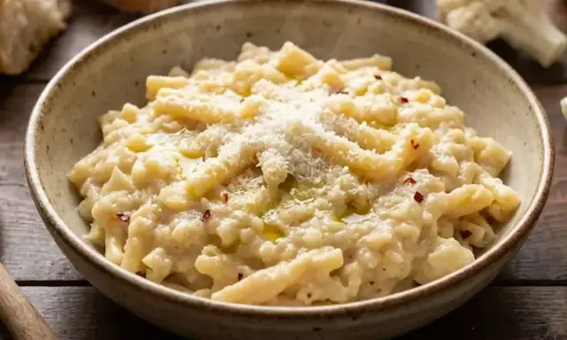 Un piatto fumante di pasta e cavolfiore cremoso, condito con parmigiano e peperoncino.