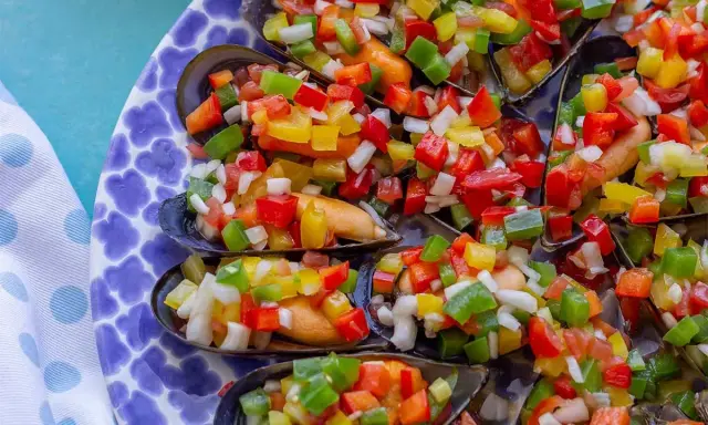 Mejillones a la vinagreta, cubiertos con una colorida mezcla de pimientos picados y cebolla.