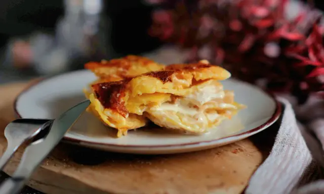 Ein Stück cremiges Kartoffelgratin mit goldbrauner Kruste auf einem Teller, bereit zum Servieren. Dieses Kartoffelgratin Rezept ist ein Genuss!