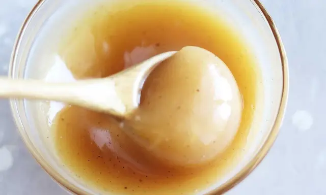 En sked lyfter krämig kolasås ur en skål. Perfekt för ditt kolasås recept!