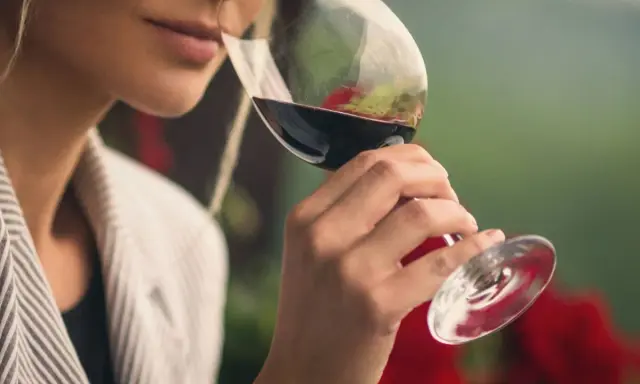 Mujer cata vino tinto, evaluando su aroma. ¿Cuánto cobra un catador de vinos por su experiencia?
