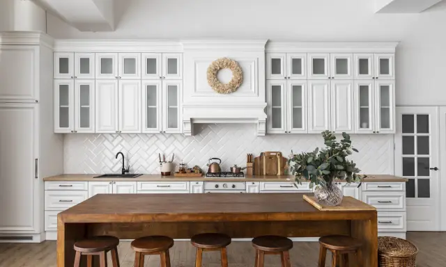 Cuisine lumineuse avec des armoires blanches et un îlot en bois massif. On dirait qu'on a réussi à faire une cuisine avec des vieux meubles, le tout dans un style rustique chic.