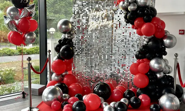 Błyszcząca ścianka z cekinami i girlandy z czerwonych, czarnych i srebrnych balonów na 18 urodziny.