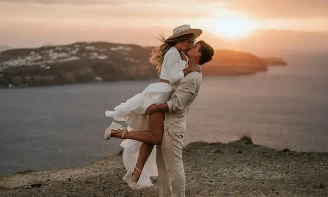 Pareja besándose al atardecer, ella en brazos de él, con un aire de bodas ibicencas.