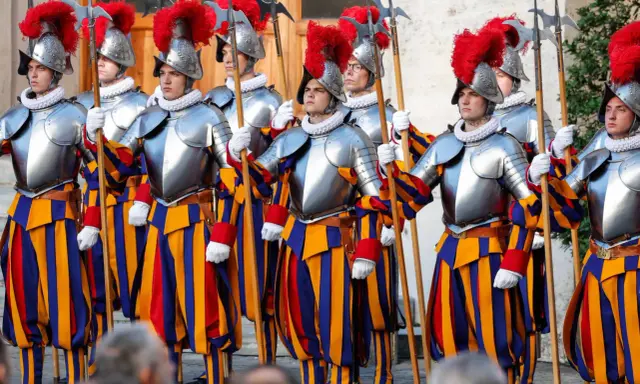 Guardie svizzere in divisa storica, con elmi piumati e alabarde, pronti a difendere la Città del Vaticano.