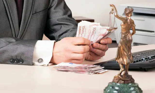 Un homme en costume compte des billets d'euros, une balance de la justice à proximité. La question se pose : le donateur peut-il vendre un bien donné en donation ?