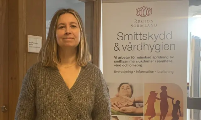 Kvinna framför banderoll om smittskydd och vårdhygien i Region Sörmland. Hon arbetar troligen med tbe kalmar.