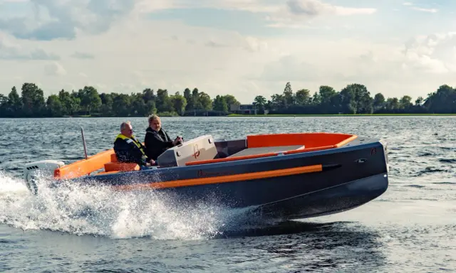 Deux hommes naviguent sur un bateau rapide, créant des éclaboussures. Le design moderne du bateau, avec ses accents orange vif, suggère une conception soignée, peut-être pour fabriquer des flaps pour bateau.