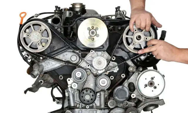 Mechanik pokazuje, jak prawidłowo zamontować pasek rozrządu w silniku samochodowym.
