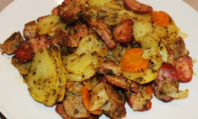 Pyszne duszonki z piekarnika: ziemniaki, kiełbasa i marchewka, doprawione ziołami.