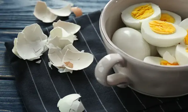 Ugotowane jajka na twardo w miseczce, obok skorupki po obieraniu. Idealne na śniadanie.