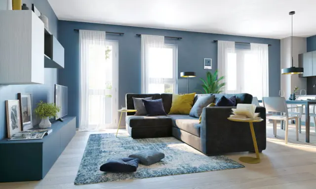 Un soggiorno moderno con divano angolare grigio scuro, cuscini blu e gialli, tappeto blu e bianco. Le pareti blu creano un'atmosfera rilassante, dimostrando che blu e grigio stanno bene insieme.