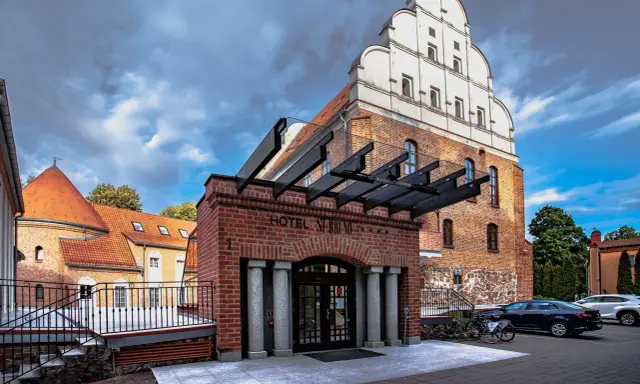 Hotel St. Bruno w Giżycku, dawniej zamek krzyżacki, z charakterystyczną ceglaną fasadą i białym szczytem.