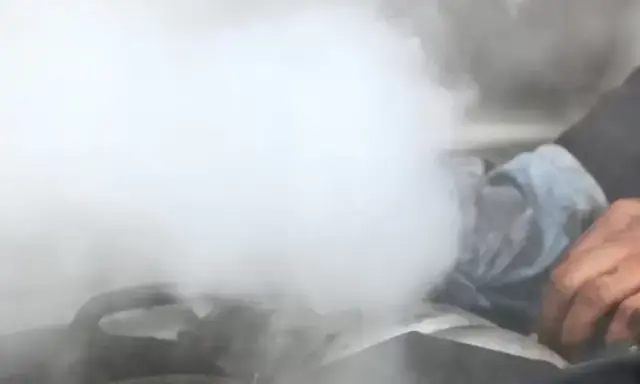 Sale humo del motor y huele a quemado. Una mano con un trapo intenta arreglar la avería.
