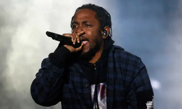 Kendrick Lamar, way out west, sjunger i en rutig skjorta med en mikrofon i handen.