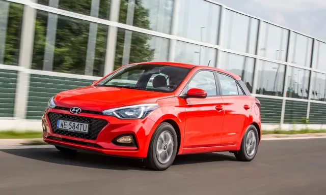 Czerwony Hyundai i20 1.2 benzyna w ruchu, z nowoczesną atrapą chłodnicy i światłami.