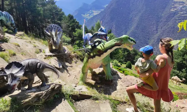 Una familia disfruta de un día prehistórico con dinosaurios en Andorra con niños. Las montañas de fondo crean un paisaje espectacular.