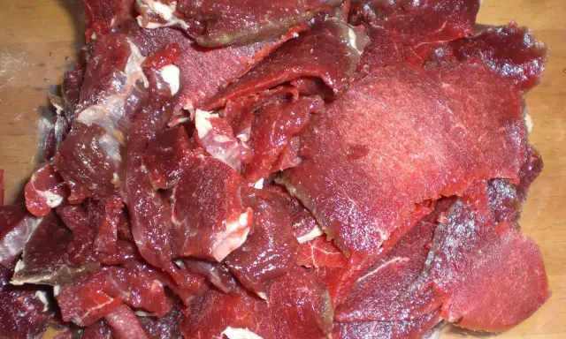 Råa, tunt skurna bitar av mörkrött kött, redo för ett läckert souvas recept.