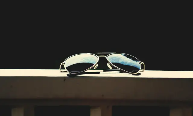 Okulary przeciwsłoneczne typu aviator leżące na drewnianej powierzchni.