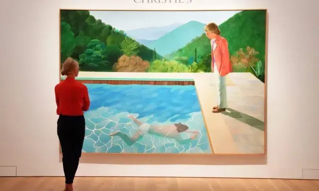 A woman in red observes David Hockney's iconic pool painting at Christie's, a testament to his significant david hockney net worth.