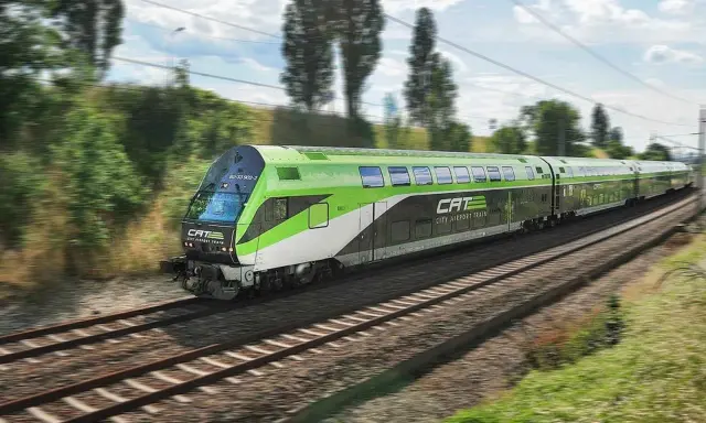 Grön och vit CAT City Airport Train susar fram på spåret, på väg till flygplatsen i Wien.