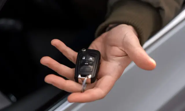 Mano sosteniendo una llave de coche moderna, lista para codificar y arrancar.