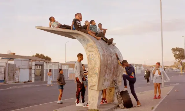 Kids gather on a unique bus stop structure, a scene that could be featured in a Belfast photo festival, capturing everyday life.