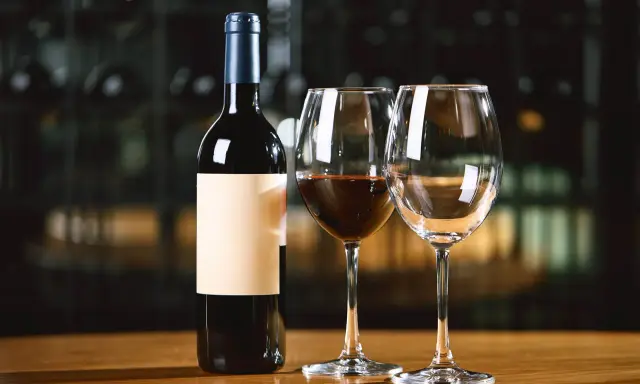 Une bouteille de vin rouge et deux verres, dont un partiellement rempli. Combien de verre dans une bouteille de vin ? La réponse est dans le plaisir de la dégustation.