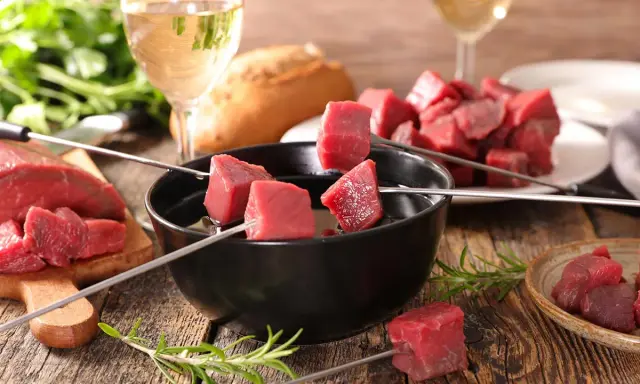 Préparation pour comment faire une fondue bourguignonne : dés de bœuf sur des brochettes, prêts à être plongés dans l'huile chaude.